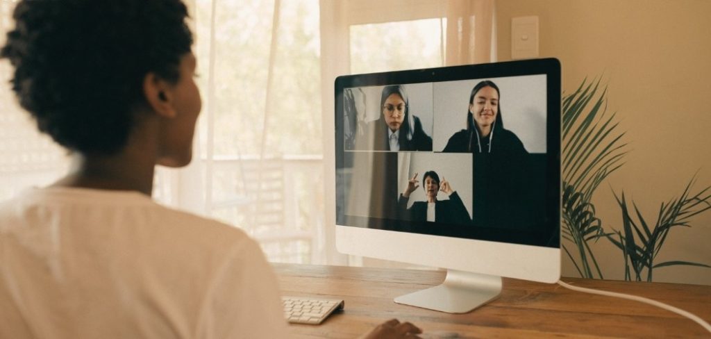 Woman staring at a computer screen showing a mindfulness Zoom meeting with three other women in the meeting