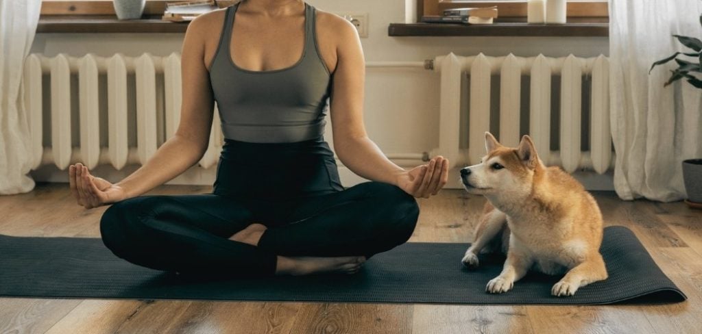 Women meditating with a dog next to her
