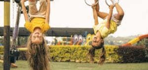 Children hanging playfully upside down on a swingset