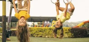 Children hanging playfully upside down on a swingset