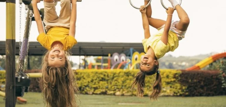Children hanging playfully upside down on a swingset
