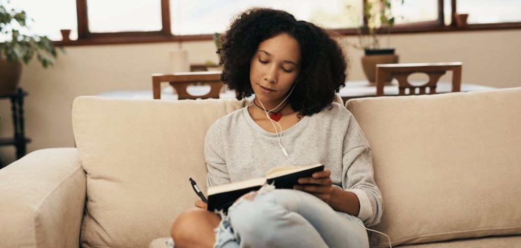 Woman sitting in the couch while manifestation journaling