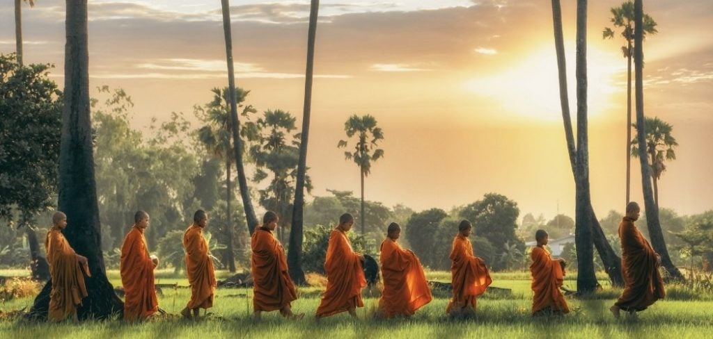 Group of monks walking through rice paddies in Asia