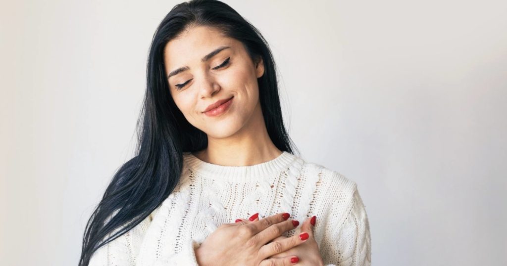 Woman putting her hands over her heart lovingly - self love affirmations