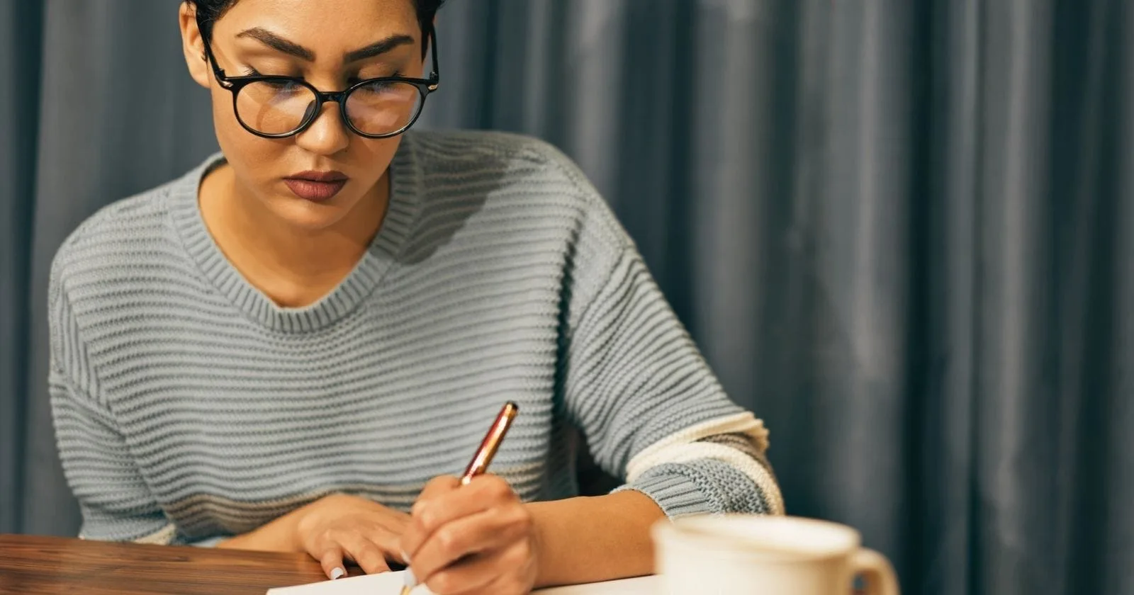 Woman writing in a mindfulness journal while seated at a table
