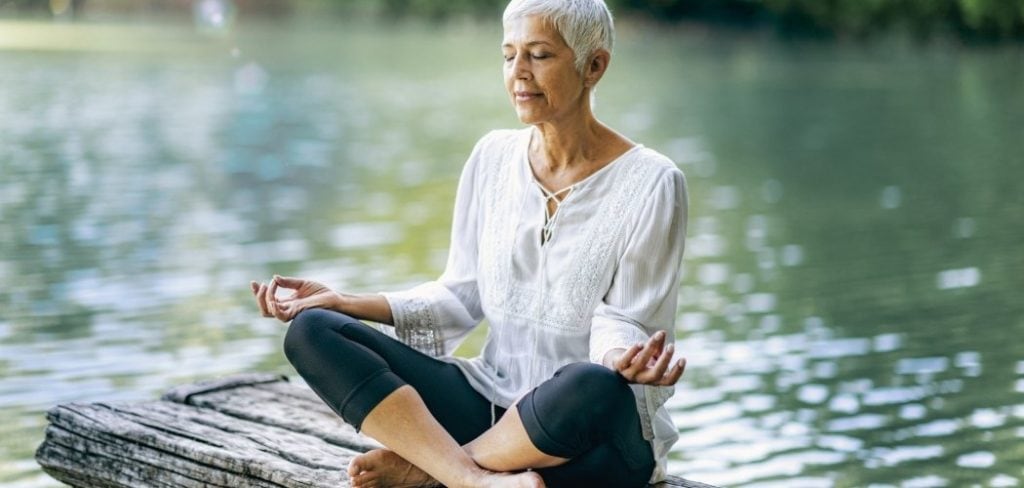 A woman practicing water meditation while sitting by a lake
