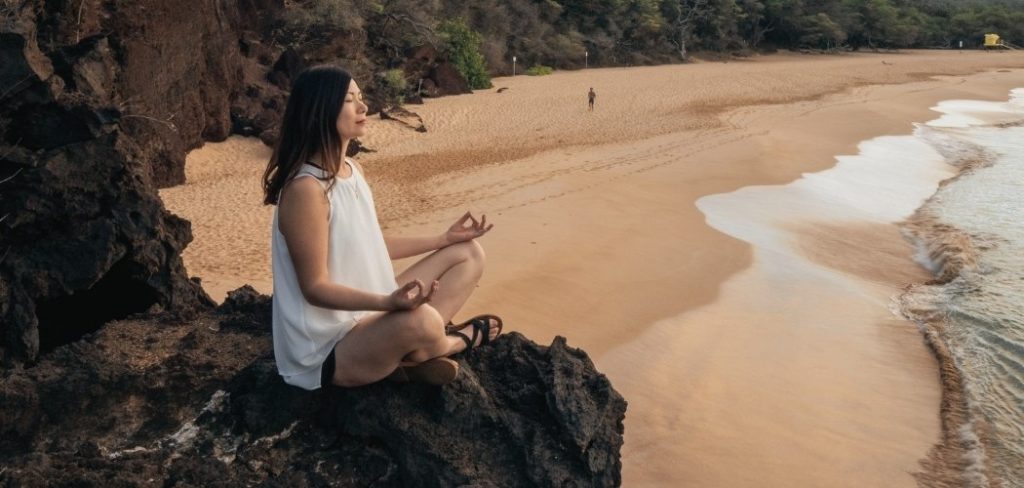Woman meditating on the beach wondering what is the goal of meditation