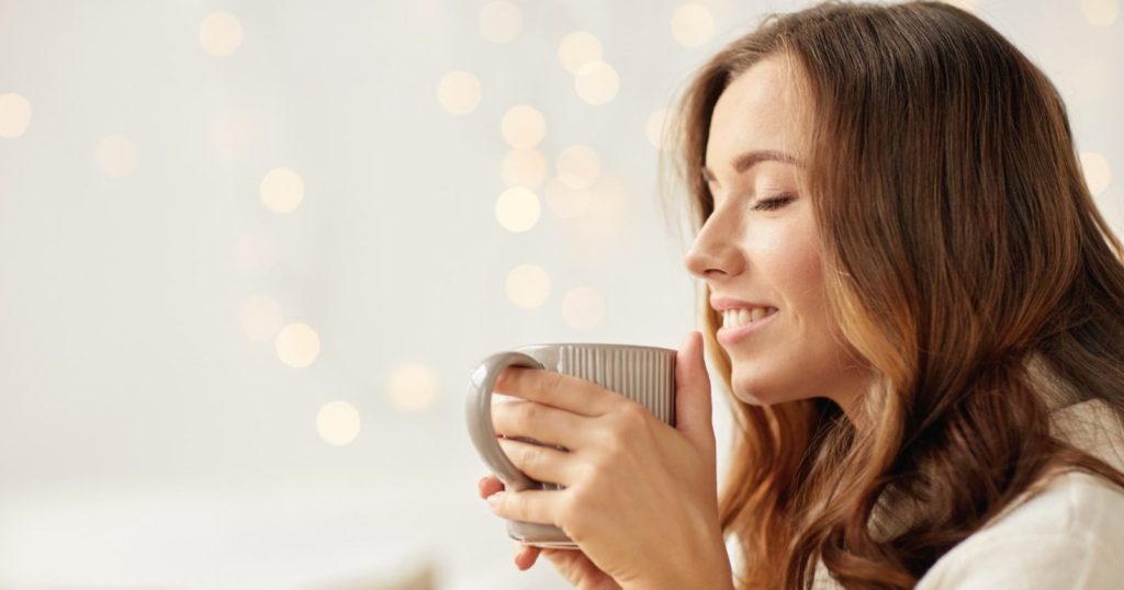 Mantras to live by - woman holding a cup of coffee and smiling