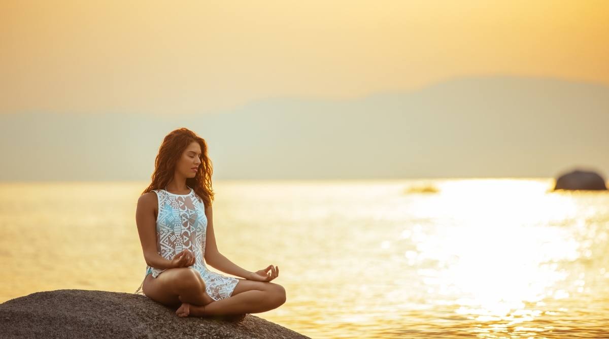 Woman meditating in front of the ocean