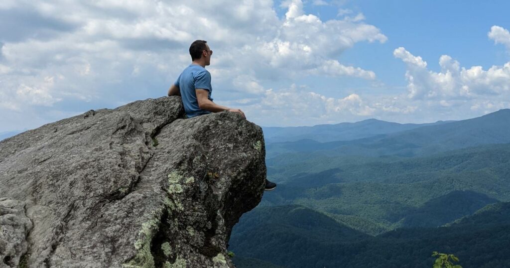 Man sitting on Blowing Rock in North Carolina staring at the horizon