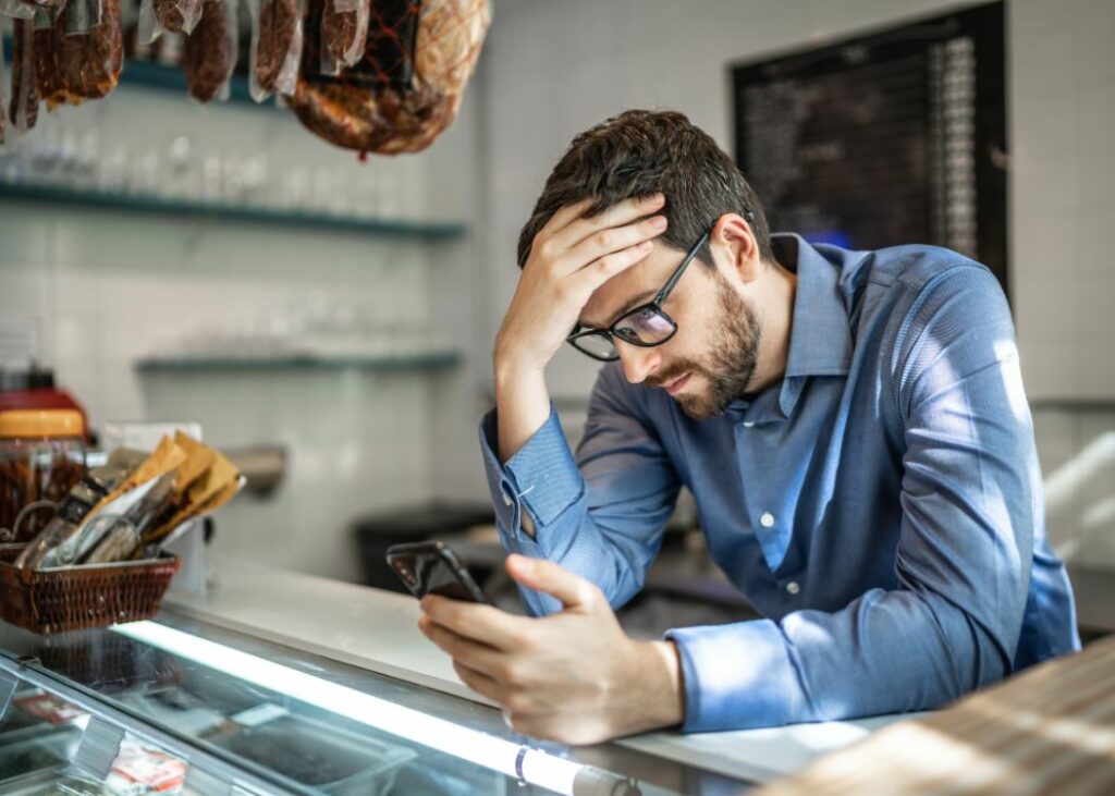 Man looking worried staring at phone while at a counter