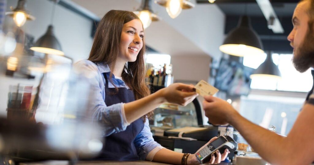 Man handing a credit card to a woman at a coffee shop