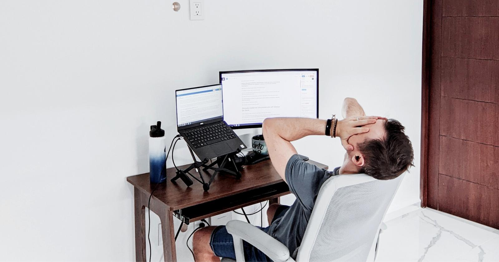Man in front of a computer with his hands on his head in a stressful pose